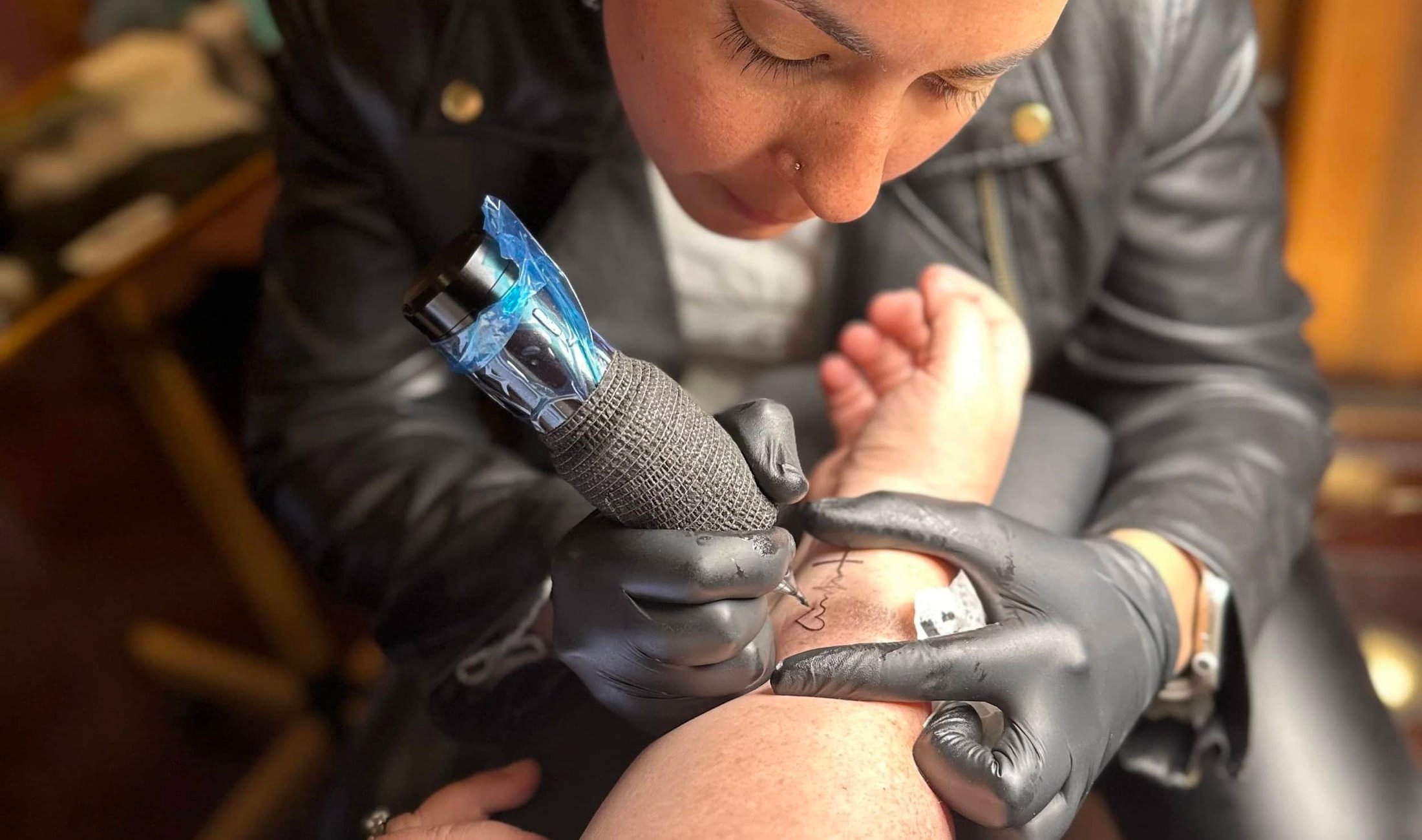 Bella performing a fine line tattoo at Picosa Ink Beauty Bar